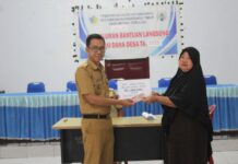 Sangadi Moyag Todulan, Roliadi Modeong (kiri), saat menyerahkan BLT secara simbolis kepada salah satu KPM di Balai Desa setempat, 22 April 2025. (foto.Ist/Pemdes Moyag Todulan)