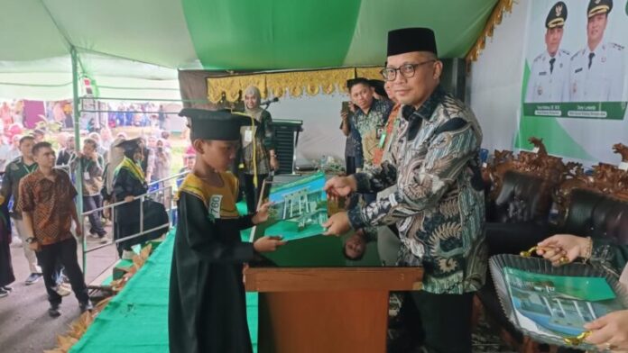 Tampak Kepala Kemenag Bolmong, Sabri M Bora, saat mewisuda Santri Bolmong, dipusatkan di jalur dua Kompleks Kantor Bupati Bolmong, Lalow, Kecamatan Lolak, Kamis 13 November 2025. (foto.Ist/Diskominfo Bolmong)