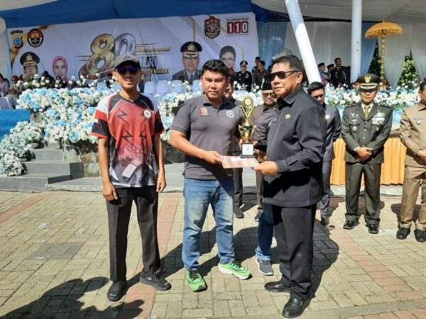 Sekdes Poyowa Besar Dua, Affan Mokodompit (kiri), saat ikut menyaksikan penyerahan piagam penghargaan kepada peserta lain pada kategori BR Fun Monte 41 Meter dalam Turnamen Menembak Kapolres Cup 2026, di lapangan Bokihotinmbang.(foto.Affan/Pemdes Poyowa Besar Dua)